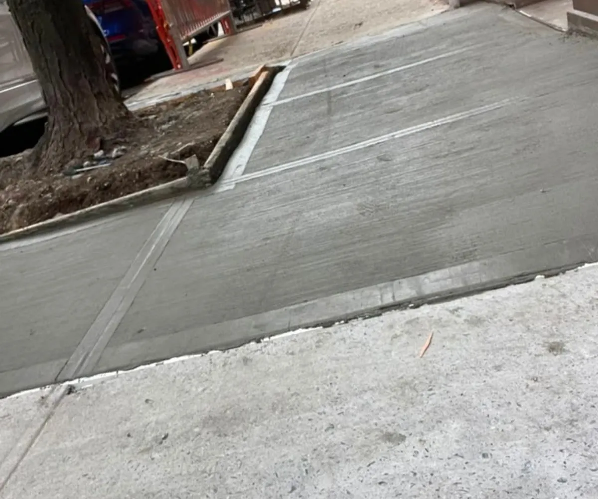 Newly replaced concrete sidewalk beside a street tree at 53 W 71st St in Manhattan after tree-root damage repair.