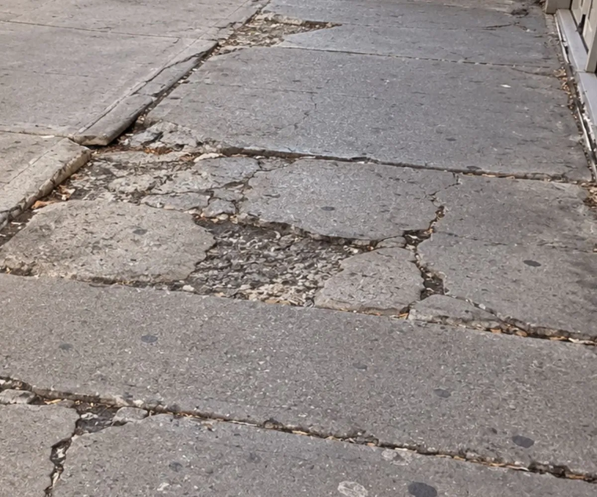 Cracked and deteriorated sidewalk slabs at 1477 2nd Avenue in Lenox Hill, Manhattan before replacement.